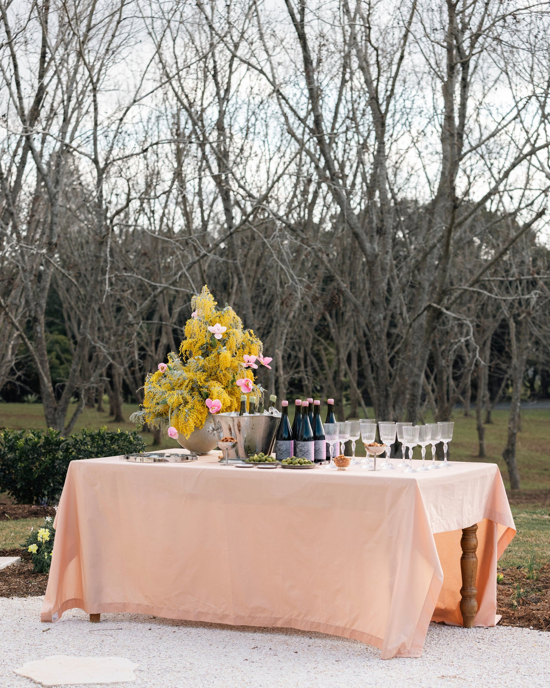Decorated outdoor table with flowers and wine glasses in a natural setting