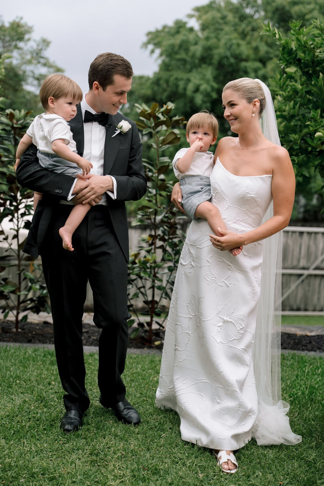 Wedding couple with two children outdoors on a grassy area